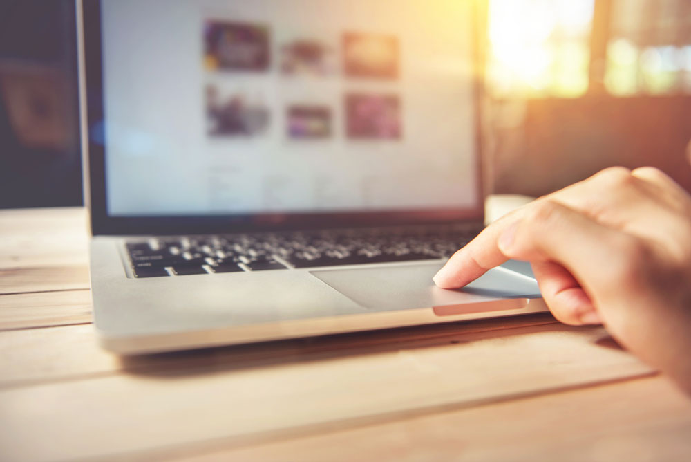 Auf dem Bild ist ein Laptop zu sehen, der durch jemanden bedient wird. Der Laptop steht auf einem hölzernen Tisch. Kund*innen können über das Internet Abo-Modelle abschließen. 